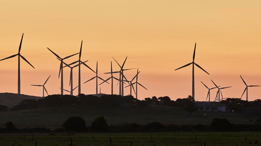 Landscape shot of wind turbines, sunset in distance