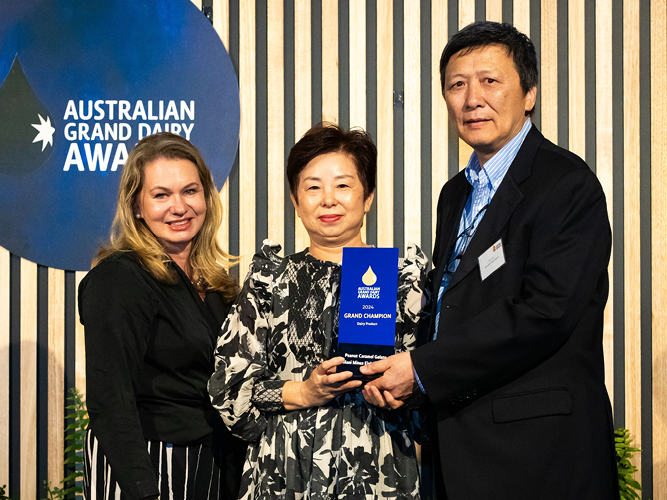 A sponsor and two award winners pose with an AGDA trophy.