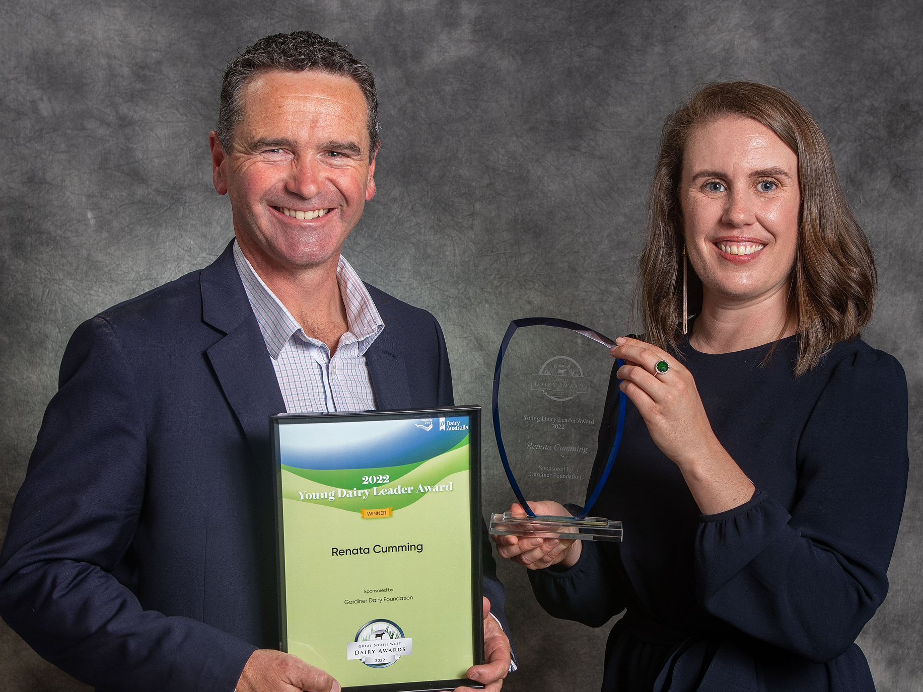Two award recipients are posing with their certificate and trophy.